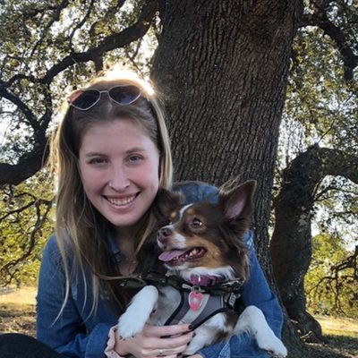 Kaitlyn holding a small brown-and-white dog under a large oak tree